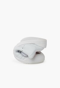 Chaussure à enfiler en cuir blanc, présentant un design incurvé, une surface texturée et une semelle lisse. Comprimé pour un affichage compact.