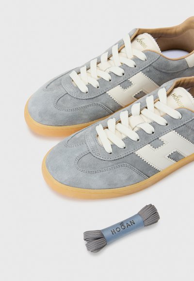Tenisii din suede gri au un design cu accente albe, șireturi crem și tălpi din cauciuc caramel. Include o pereche suplimentară de șireturi gri.