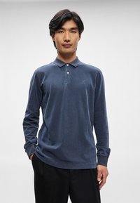 Μακρυμάνικο ναυτικό μπλουζάκι πόλο από μαλακό ύφασμα, με κλασικό γιακά, κλείσιμο με κουμπιά και διακριτό λογότυπο της μάρκας στο αριστερό στήθος.