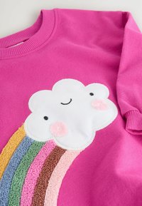 Rosa Sweatshirt mit einer weißen Wolke mit einem lächelnden Gesicht und weichen Wangen. Darunter ein mehrfarbiges, strukturiertes Regenbogen-Design.