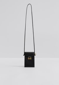 Μαύρη δερμάτινη τσάντα ώμου με δίπλωμα καπακιού, μεταλλικές χρυσές λεπτομέρειες και ρυθμιζόμενο λουράκι. Λείο υφή και συμπαγές ορθογώνιο σχήμα.