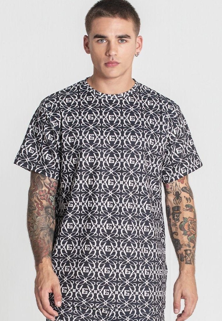 Čierne a biele tričko s geometrickými vzormi, krátkymi rukávmi, klasickým výstrihom a voľným strihom. Materiál sa zdá byť hladký.