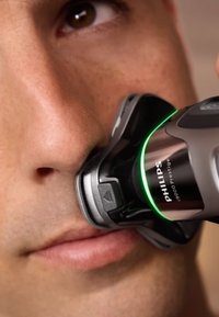 Philips Norelco 9000 Prestige elektrische scheermachine, met een slank zwart en zilver ontwerp, groene LED-accent, ingewikkelde kopdetails en ergonomische vorm.