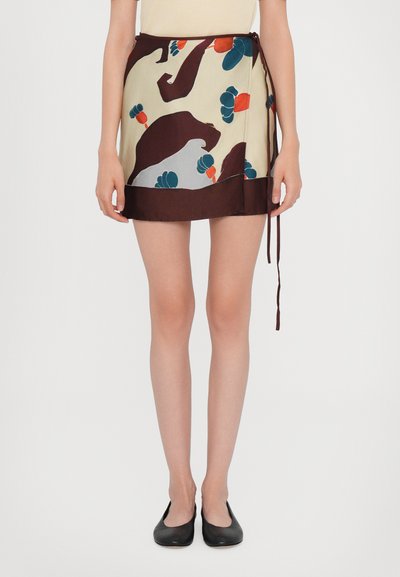 Falda envolvente de seda color crema con un colorido patrón floral, dobladillo marrón oscuro y cierre de lazo. Textura suave con un diseño ligero.