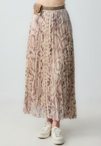 Gonna maxi plissettata beige con motivo pitonato. Presenta una cintura goffrata effetto coccodrillo con fibbia. Abbinata a sneaker bianche.