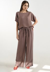 Losse mauve tweedelige outfit gemaakt van textiel; bevat een kortmouwtop en brede broekspijpen met een elastische tailleband.