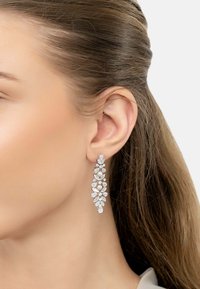 Silver chandelier earring featuring multiple clear rhinestones and small pearls in a floral design, hanging below the earlobe.