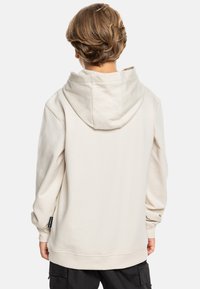Beige hoodie met een grote capuchon, voorzien van ribgebreide manchetten en zoom. De stof lijkt zacht en gestructureerd, ontworpen voor een relaxte pasvorm.
