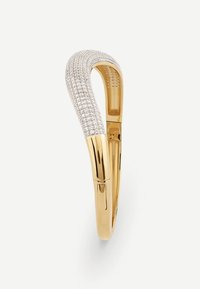 Gold-tone bangle with a curved design, featuring a row of small, clear diamonds along one side and a textured finish on the interior.