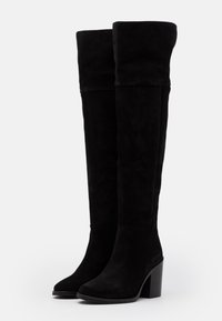 Botas negras por encima de la rodilla hechas de ante, con un tacón cuadrado y un borde enrollado en la parte superior, con una textura suave y una silueta elegante.
