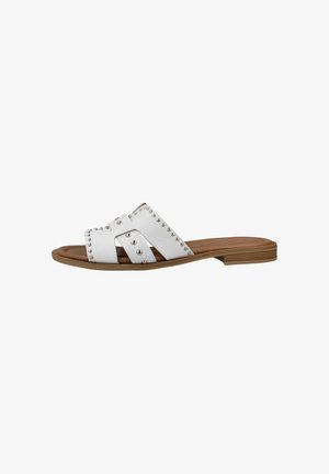 Sandalia plana blanca con tachuelas plateadas, puntera abierta y suela marrón con tacón bajo apilado.