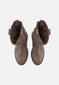 Brown suede ankle boots with a rounded toe, zipper closure, and soft interior lining. Features a stitched sole and dual pull tabs.