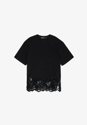 Czarna koszulka z krótkim rękawem, z koronkowym dołem o falbaniastym kształcie, który kontrastuje z gładkim materiałem powyżej.