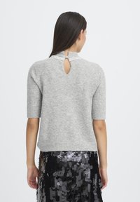 Maglione grigio a maniche corte con finitura testurizzata, caratterizzato da una apertura a goccia sulla schiena e da una scollatura decorata con perle.