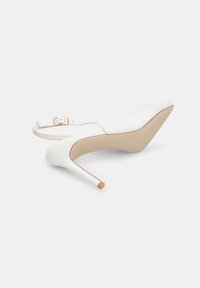 Bele čevlje s konico in slingback zapiranjem, z ozkim stiletto peto in zlatim detajlom s sponko. Gladko površje in gola notranja obloga.