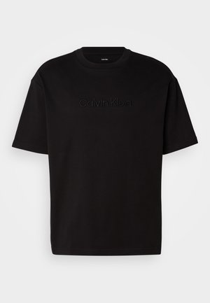 Crna pamučna majica s kratkim rukavima, koja na prednjoj strani ima utisnut "Calvin Klein" logo, okrugli izrez i opušteni kroj.