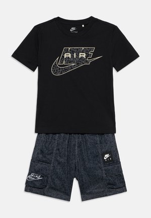 Fekete Nike Air rövid ujjú póló mintás logóval, sötétszürke mintás cargo rövid nadrággal, amelyen Nike Air foltok találhatók.