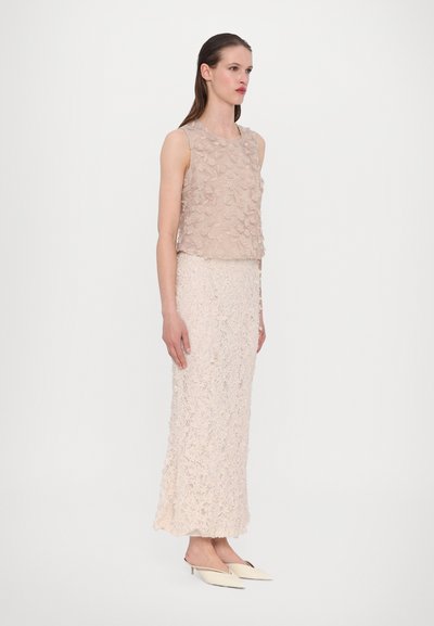 Beige sleeveless top with textured floral appliqués paired with a long, fitted skirt featuring a similar floral pattern. Pointed heels.