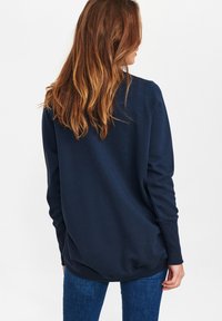 Sudadera azul marino con un corte holgado, puños y dobladillo acanalados. Textura suave, mangas largas y escote redondo.