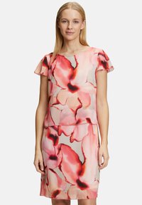 Blumenkleid mit einem leichten, transparenten Overlay. Es hat rote und rosa Muster auf einem beigen Hintergrund, kurze Ärmel und eine taillierte Passform.