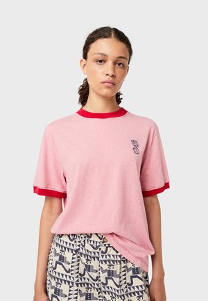 Roze T-shirt met korte mouwen, voorzien van een rode ribbelboord bij de hals en mouwen. Heeft een klein grafisch ontwerp op de linkerborst.