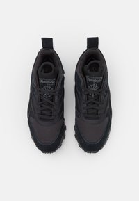 Chaussures de sport noires en mesh et daim, avec un col rembourré, des lacets ronds et des semelles en caoutchouc texturées.