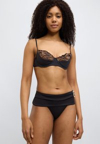 Σετ μαύρου μπικίνι με ενισχυμένο σουτιέν που διαθέτει δαντέλα με λεοπάρ μοτίβο και ρυθμιζόμενες τιράντες· μαύρο σλιπ με ψηλή μέση και διακοσμητική αγκράφα.