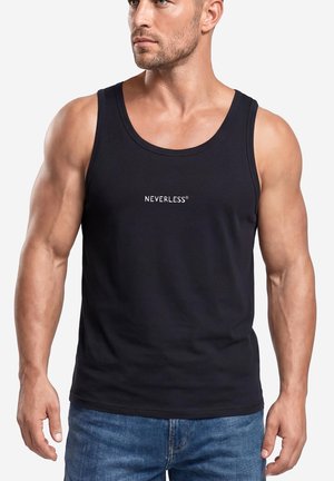 Muskelbepackter Mann trägt ein schwarzes Tanktop mit weißem Text "NEVERLESS", kombiniert mit blauen Jeans, leicht nach links blickend.