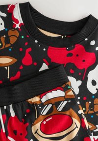 Schwarzes Baumwoll-Outfit mit Rundhalsausschnitt und elastischem Bund, verziert mit bunten, spielerischen Weihnachtsmotiven und -designs.