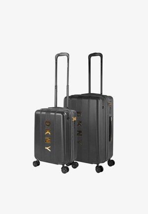 Set de equipaje negro de carcasa dura con diseño acanalado, logo dorado de DKNY, dos maletas con ruedas giratorias, asas telescópicas y ruedas giratorias.