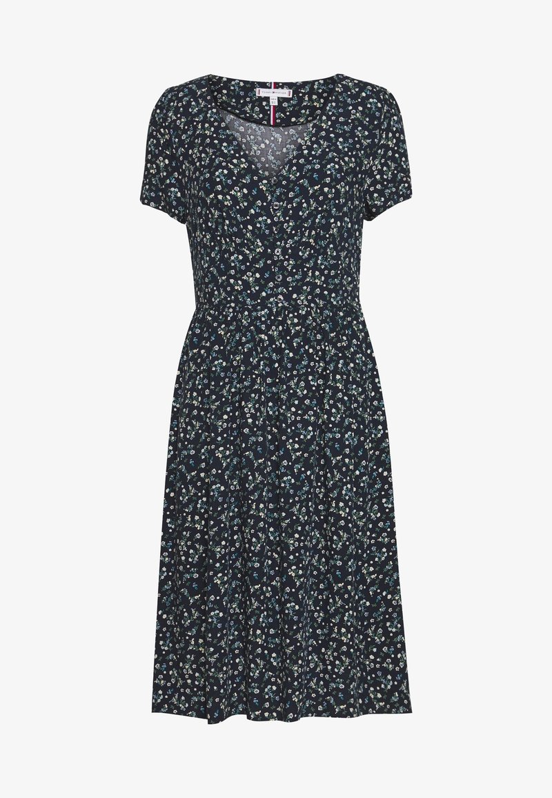 Granatowa sukienka w kwiaty z krótkimi rękawami, z dekoltem w łódeczkę, dopasowaną talią i zwiewnym dołem, ozdobiona małymi białymi i niebieskimi kwiatami.