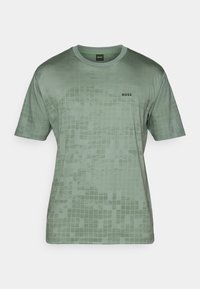 T-shirt vert à manches courtes en tissu lisse, avec un motif en damier et un logo noir "BOSS" sur la zone gauche de la poitrine.