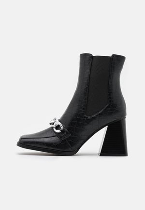 Bottines noires à texture crocodile, avec des panneaux latéraux élastiques, des détails en métal argenté et un talon bloc géométrique. Design à bout pointu.