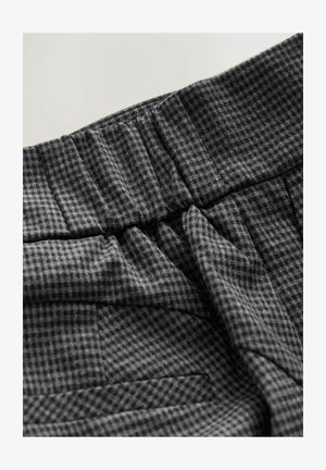 Tessuto grigio a motivi che presenta una superficie texture con dettagli plissettati e una vita elasticizzata. Il motivo è composto da piccoli quadrati.