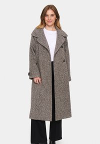 Cappotto lungo in misto lana con un motivo a zigzag marrone e crema. Presenta un ampio colletto, bottoni doppi e una vestibilità over. 