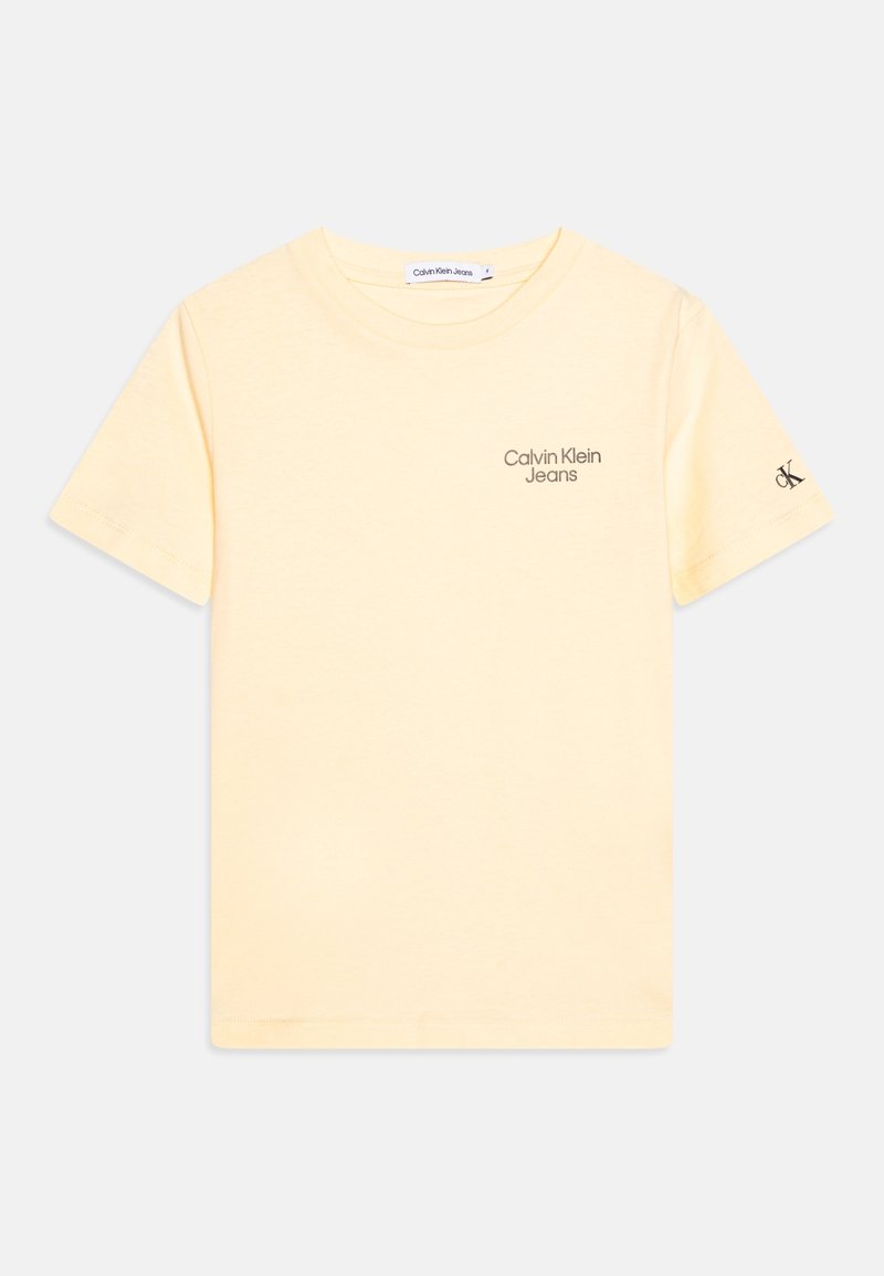 Světle žluté bavlněné tričko s krátkým rukávem, na hrudi je šedé logo "Calvin Klein Jeans" a malé logo na rukávu.