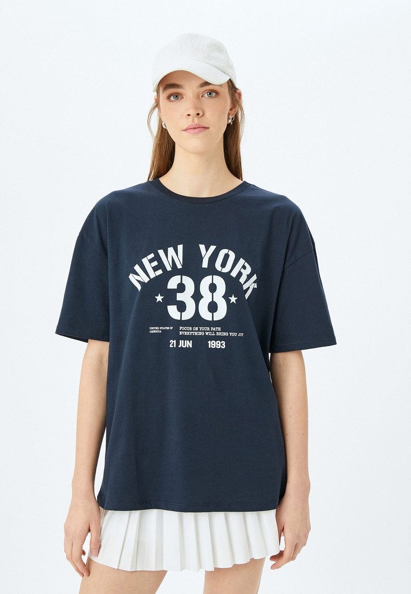 Camiseta de color azul marino con mangas cortas, que presenta un estampado gráfico y texto en blanco que dice "NEW YORK 38". Material blando de algodón, corte relajado.