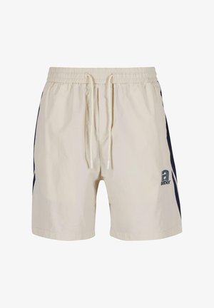 Bañadores beige con cinturilla ajustable con cordón, rayas laterales en azul marino y logo bordado en el frente. Textura ligera y suave.