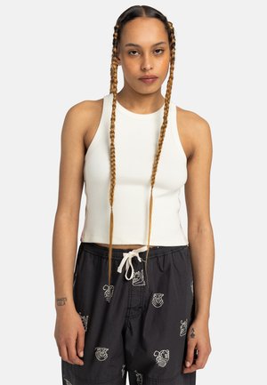 White ribbed crop top with a high neckline, paired with black shorts featuring white animal patterns and a drawstring.