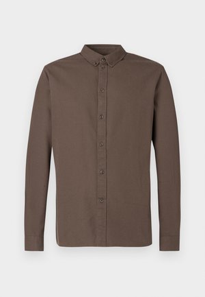 Tumši brūna, ar garām piedurknēm un pogām aiztaisāma krekls ar klasisku apkakli, astoņām priekšējām pogām un gludu, vieglu auduma tekstūru.