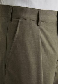 Pantaloni tailored de culoare verde măslin, cu o textură netedă, având plisuri frontale, un talie plată și buzunare laterale.