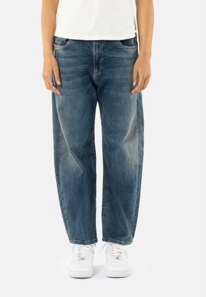 Lichtblauwe denim jeans met een losse pasvorm, voorzien van een klassiek vijf-pocket ontwerp. Gecombineerd met witte sneakers, wat een casual stijl toont.