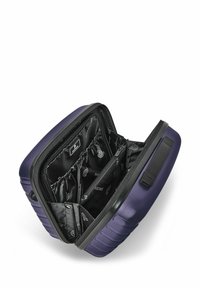 Valigia rigida compatta di colore blu navy aperta per mostrare l'interno organizzato di colore nero con tasche con cerniera ed elastiche, e una maniglia nera sul lato.