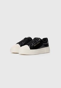 Baskets en cuir verni noir avec embouts et semelles en caoutchouc blanc, comportant le logo "Armani Exchange" sur les côtés et la semelle.