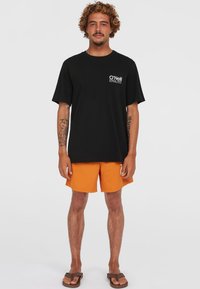 Camiseta negra de O'Neill con logo en el frente, pantalones cortos de baño naranjas y chanclas marrones. Ajuste casual, mangas cortas, colores sólidos y diseño sencillo.