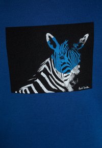 T-shirt in cotone blu con una grafica quadrata nera raffigurante una zebra, con strisce bianche e blu e la firma dell'artista nell'angolo.
