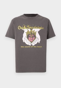 Camiseta de algodón gris con un gráfico central de manos sosteniendo un corazón en llamas, con texto impreso arriba y abajo en colores amarillo y rosa.