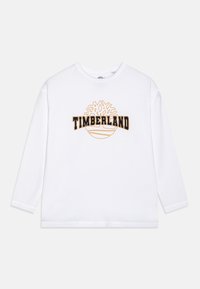 Long-sleeve white cotton shirt featuring a black and orange "TIMBERLAND" logo with a tree design above it. Classic crew neckline and relaxed fit.