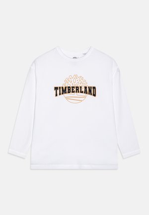 Long-sleeve white cotton shirt featuring a black and orange "TIMBERLAND" logo with a tree design above it. Classic crew neckline and relaxed fit.