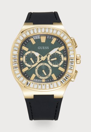 Orologio dorato con quadrante verde testurizzato, tre sottodial e dettagli in cristallo. Cinturino in gomma nera, design della cassa rotonda sovradimensionata.